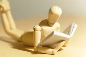 wooden figure reading a business book