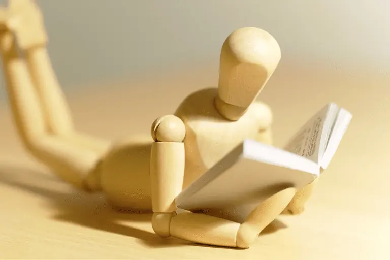 wooden figure reading a business book